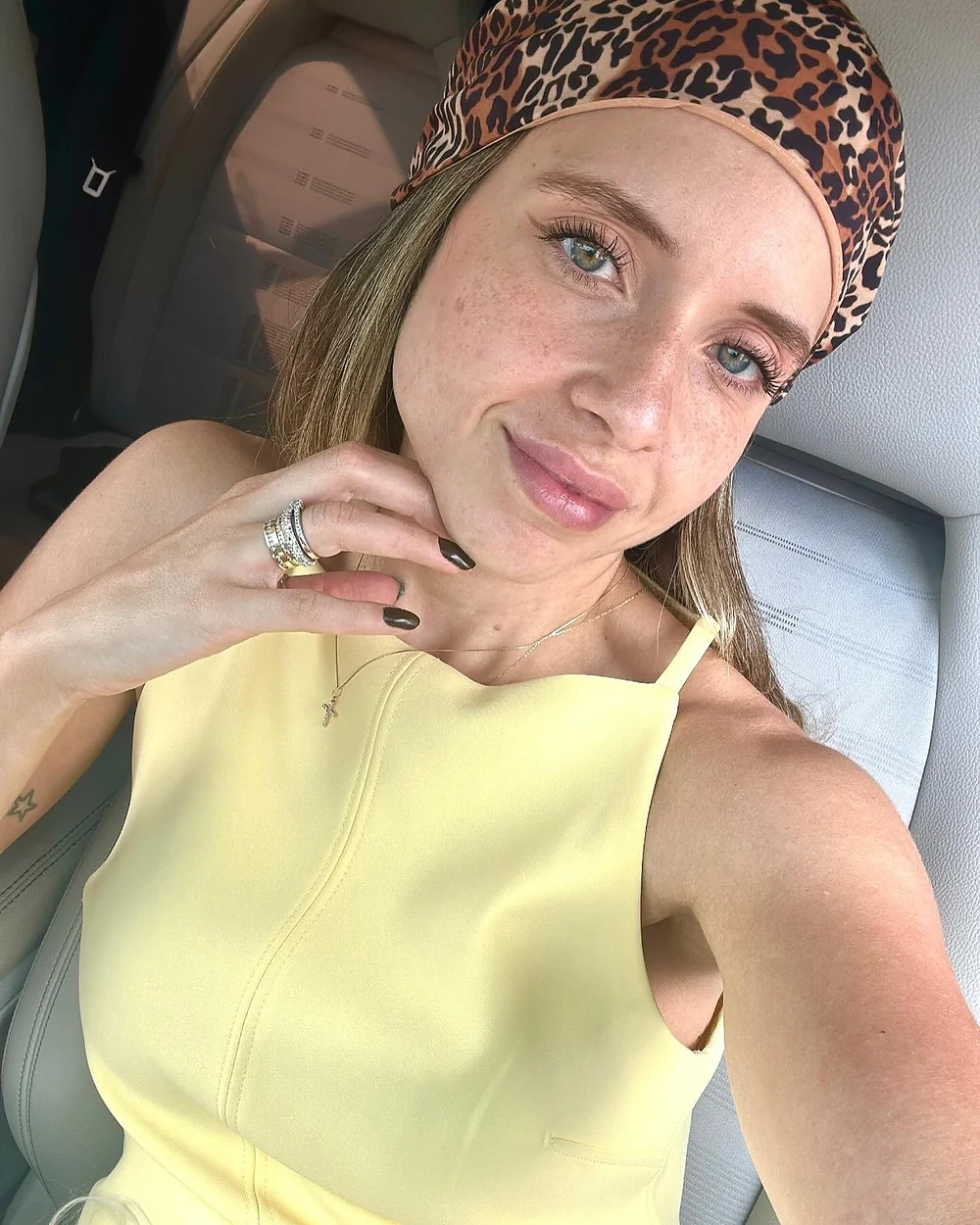 Sthéfany em uma selfie de perto, com lenço de estampa de onça no cabelo e blusa amarela