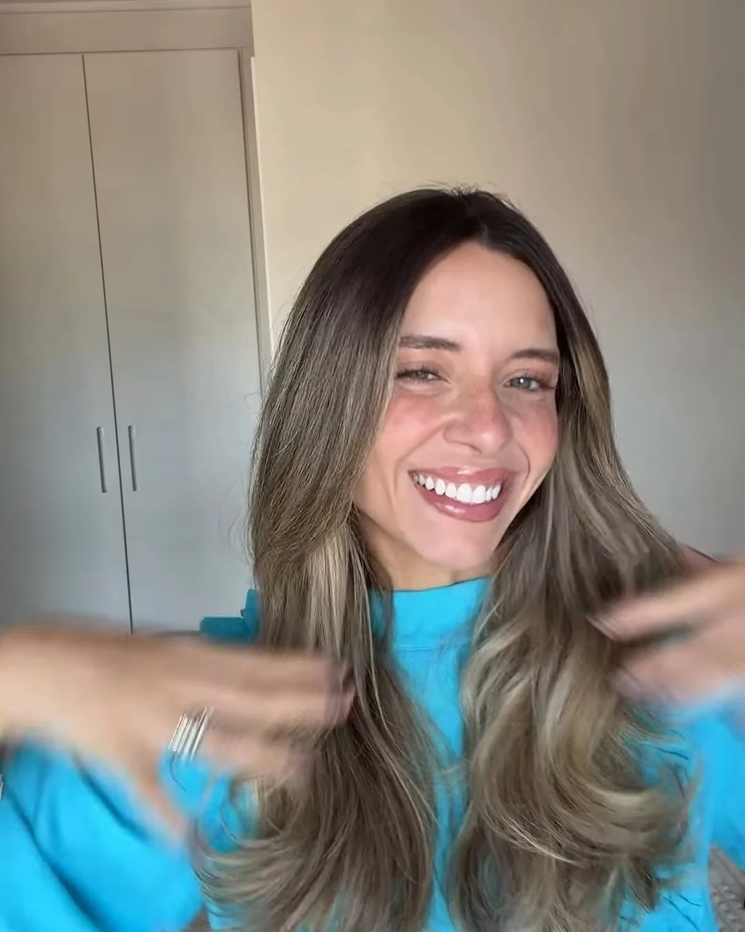 Sthéfany sorrindo para a câmera com blusa azul-turquesa e cabelo solto