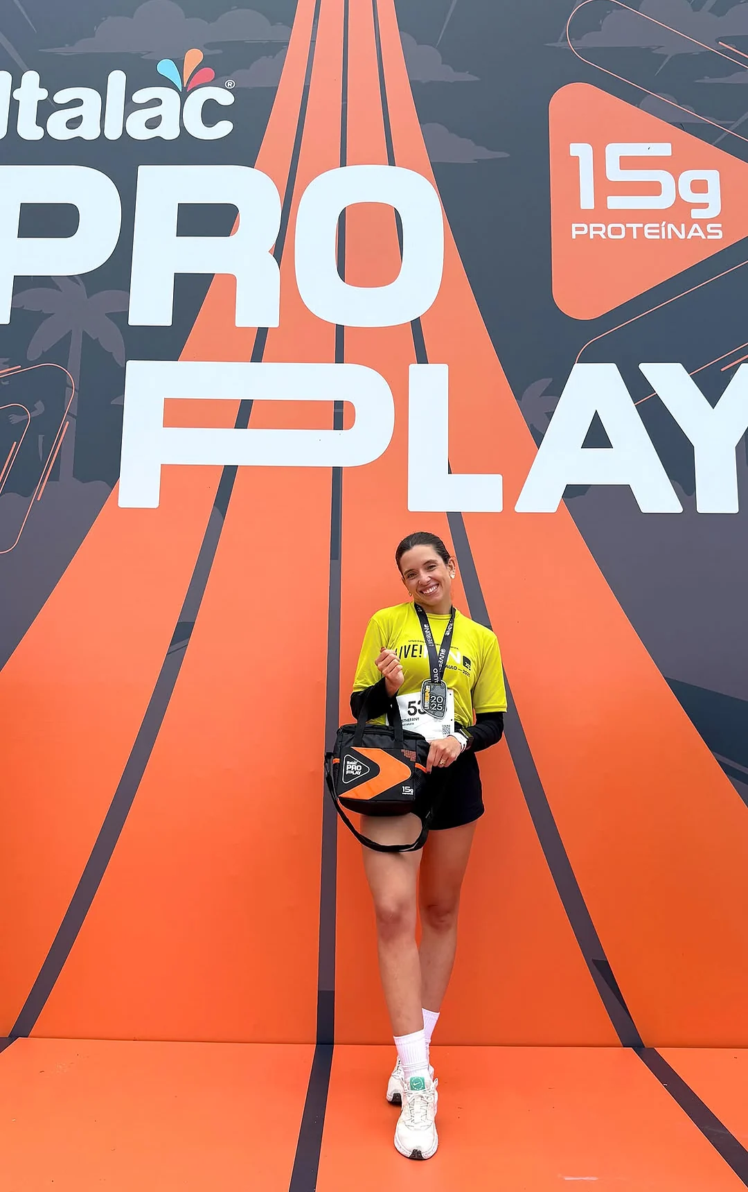 Sthéfany de camisa amarela da Live Run diante do painel laranja da Italac ProPlay