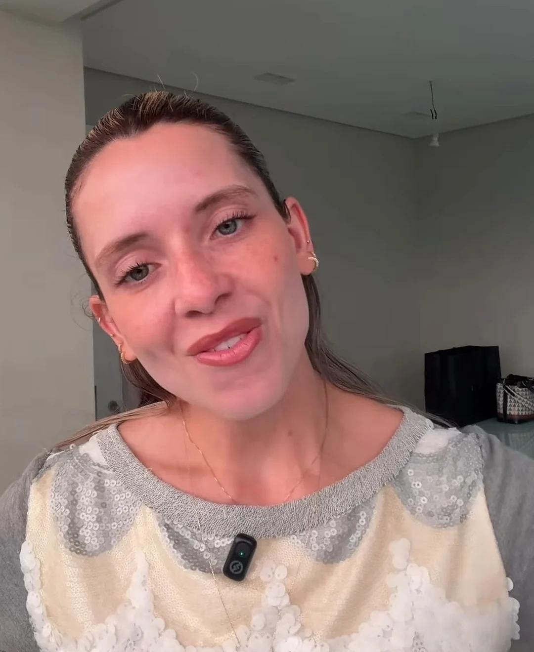 Sthéfany falando para a câmera em um vídeo, de blusa cinza com detalhes claros